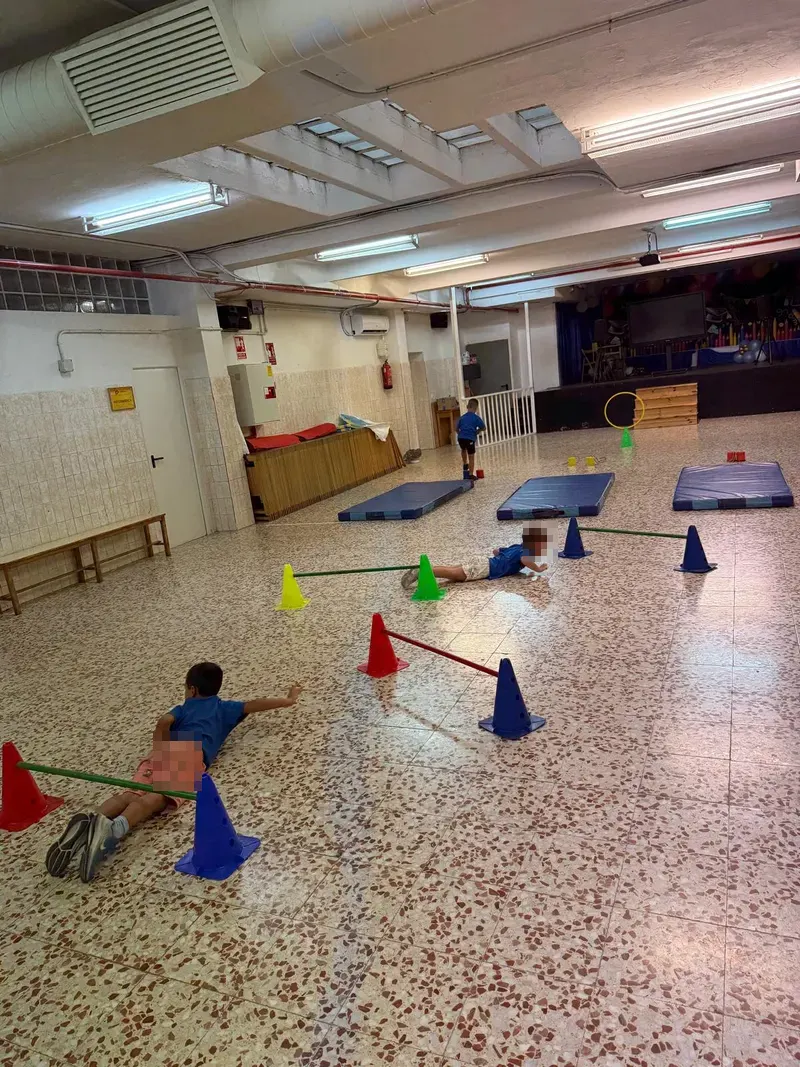 Gimnasio cubierto del colegio con conos y colchonetas para un circuito de psicomotricidad